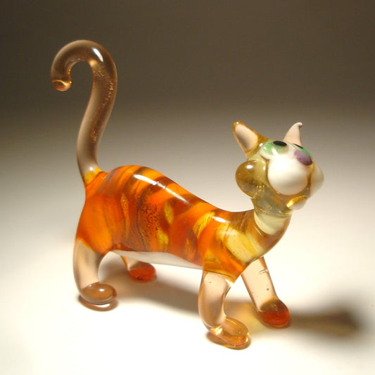 A hand-blown glass cat figurine with orange, yellow, and white marbled patterns.