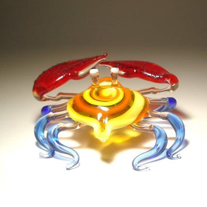 Front view of a glass crab figurine with vibrant red claws, showcasing its detailed colorful shell and legs.