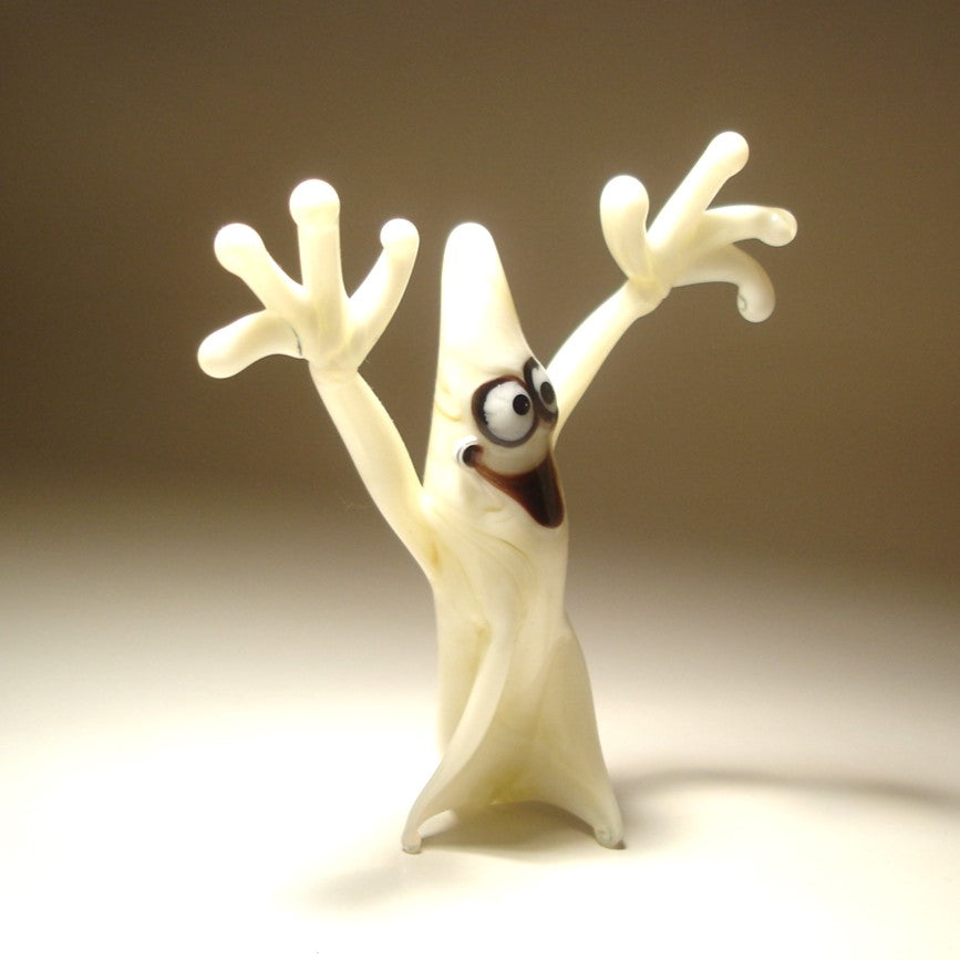 A glass white ghost figurine with its arms raised displaying its friendly and cheerful demeanor.