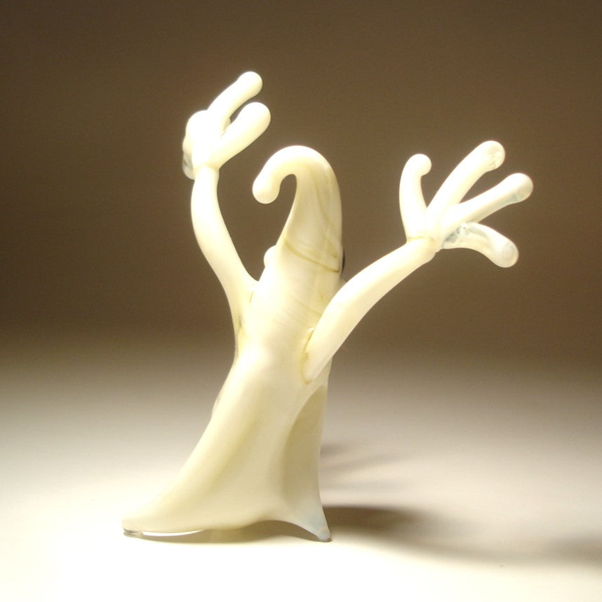 A small sculptural figurine of a ghostly form with two raised arms.