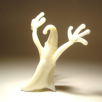 A small sculptural figurine of a ghostly form with two raised arms.