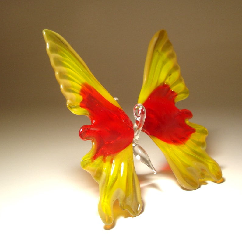 A handcrafted glass butterfly sculpture with vibrant yellow and red wings.