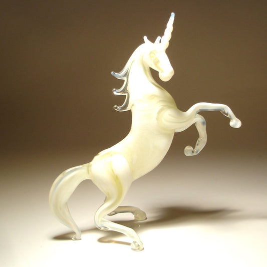 A side view of a glass white unicorn figurine, emphasizing its elegant posture and the intricate design of its flowing mane and tail