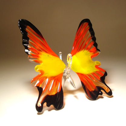 A hand-blown glass butterfly sculpture with vibrant red, yellow, and black wings
