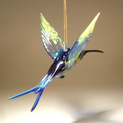 Back view of a glass, blue and Yellow swallowtail hummingbird ornament suspended from a thread.