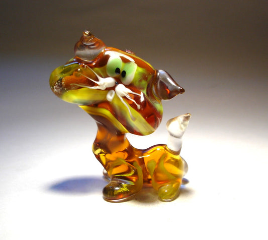 A front view of a glass striped cat figurine, showcasing its green eyes, detailed facial features, and vibrant yellow on brown striped pattern.