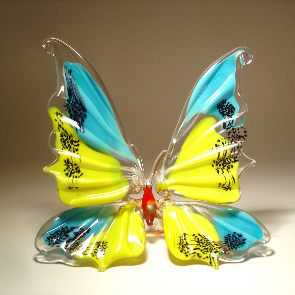 A hand-blown glass butterfly sculpture with vibrant yellow and turquoise wings, decorated with black dots and a small red body.