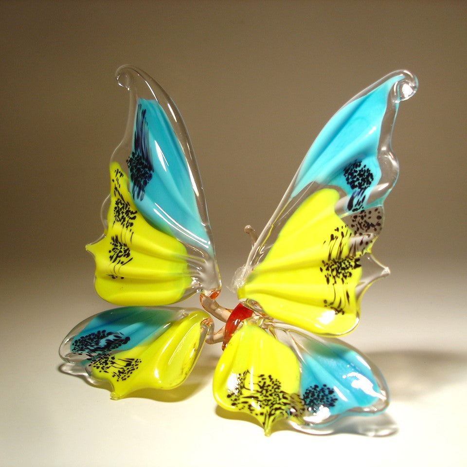 A handmade glass butterfly with blue and yellow wings.