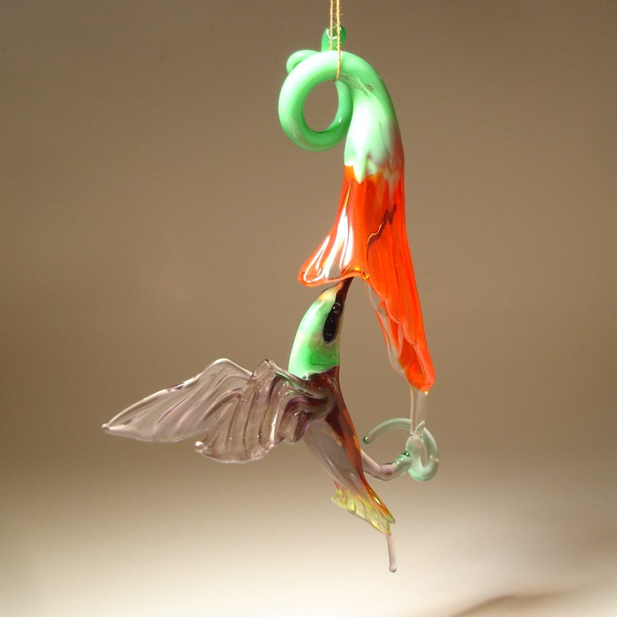 Glass Red flower and a Green and Purple hummingbird suspended from it,  as  if drinking nectar