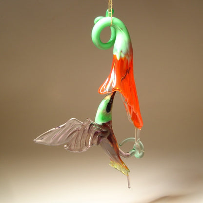 Glass Red flower and a Green and Purple hummingbird suspended from it,  as  if drinking nectar