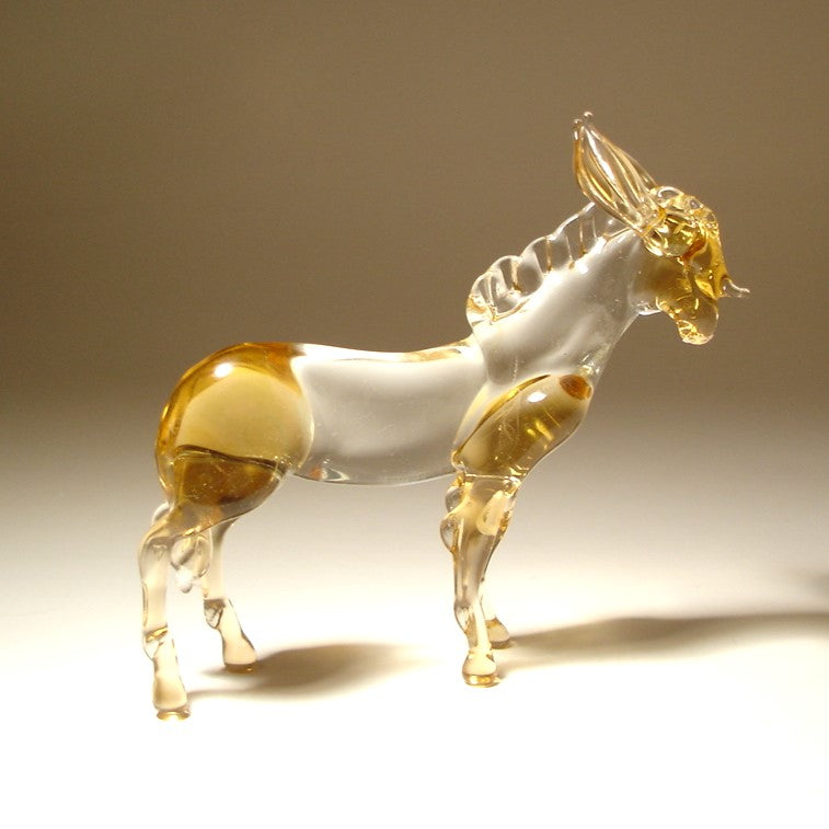 A small glass donkey figurine with a transparent white body and amber-golden translucent sections
