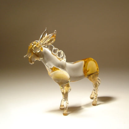 A small decorative figurine of a donkey made from transparent frosted glass with amber-colored highlights