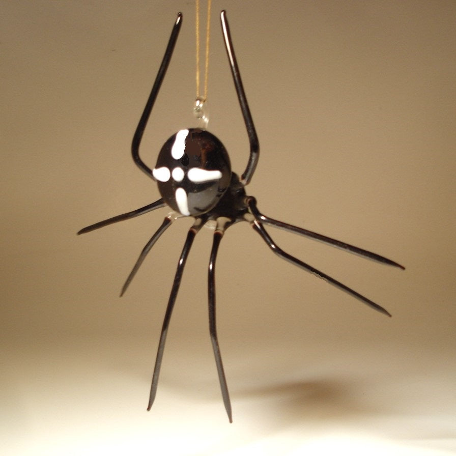 A hanging spider ornament with a glossy black body and legs and white cross on the back markings.