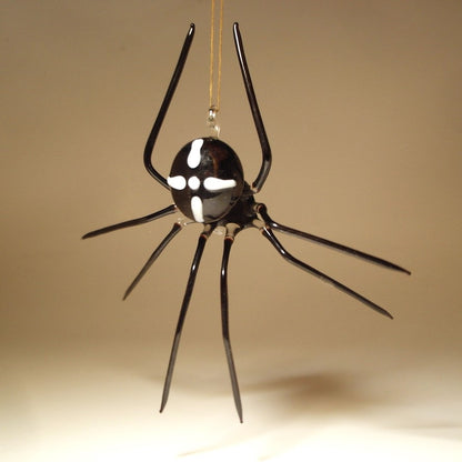 A hanging spider ornament made of glossy black glass with white decorative markings on its body.