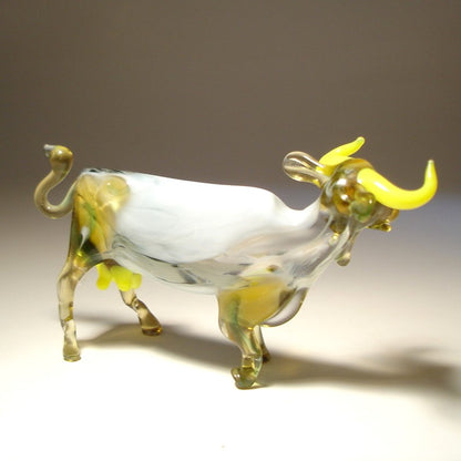 Back side of a white glass cow with yellow horns.