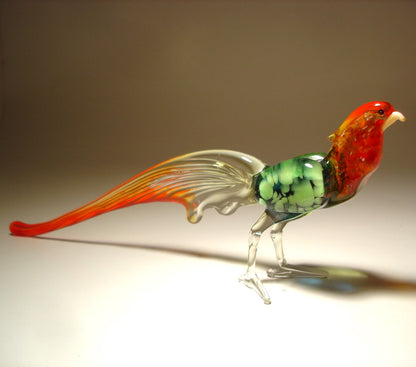 Side angle of the glass pheasant figurine, capturing the elegant curve of its long red and clear tail feathers.