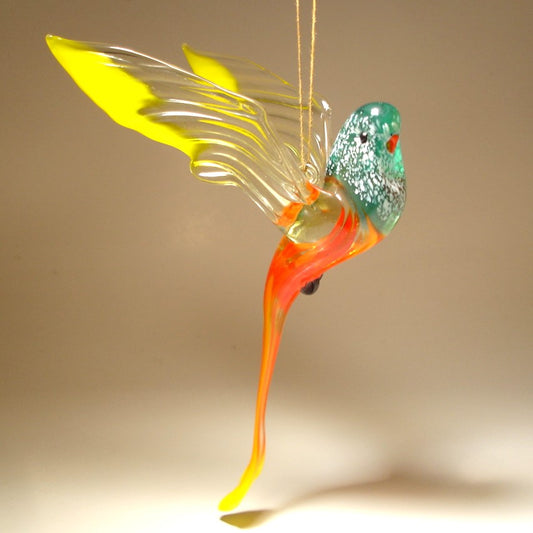 The glass parakeet ornament is depicted in striking yellow, red and green hues with red beak and feet.