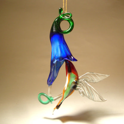 Glass red and green hummingbird figurine hovering next to a vibrant blue flower ornament