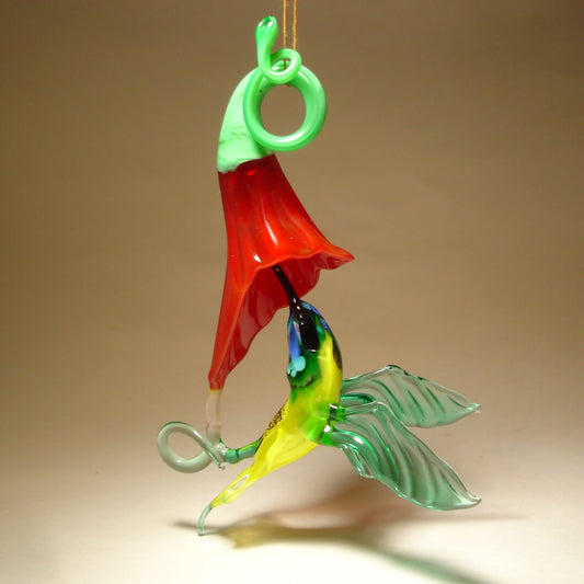 Glass Red flower and a yellow and Green hummingbird suspended from it,  as  if drinking nectar