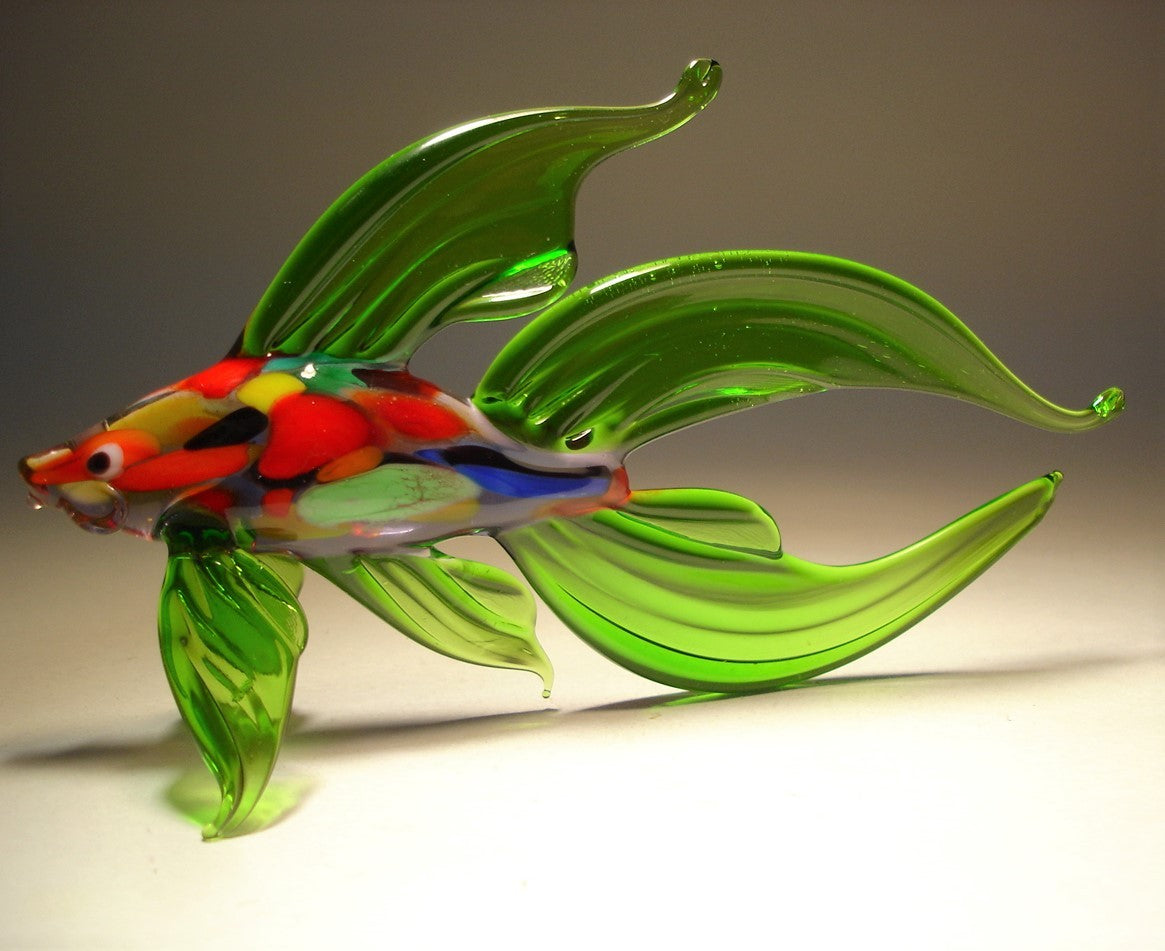 A side profile of the handmade green glass Betta fish figurine, highlighting its long, graceful fins that fan out elegantly behind the body. 