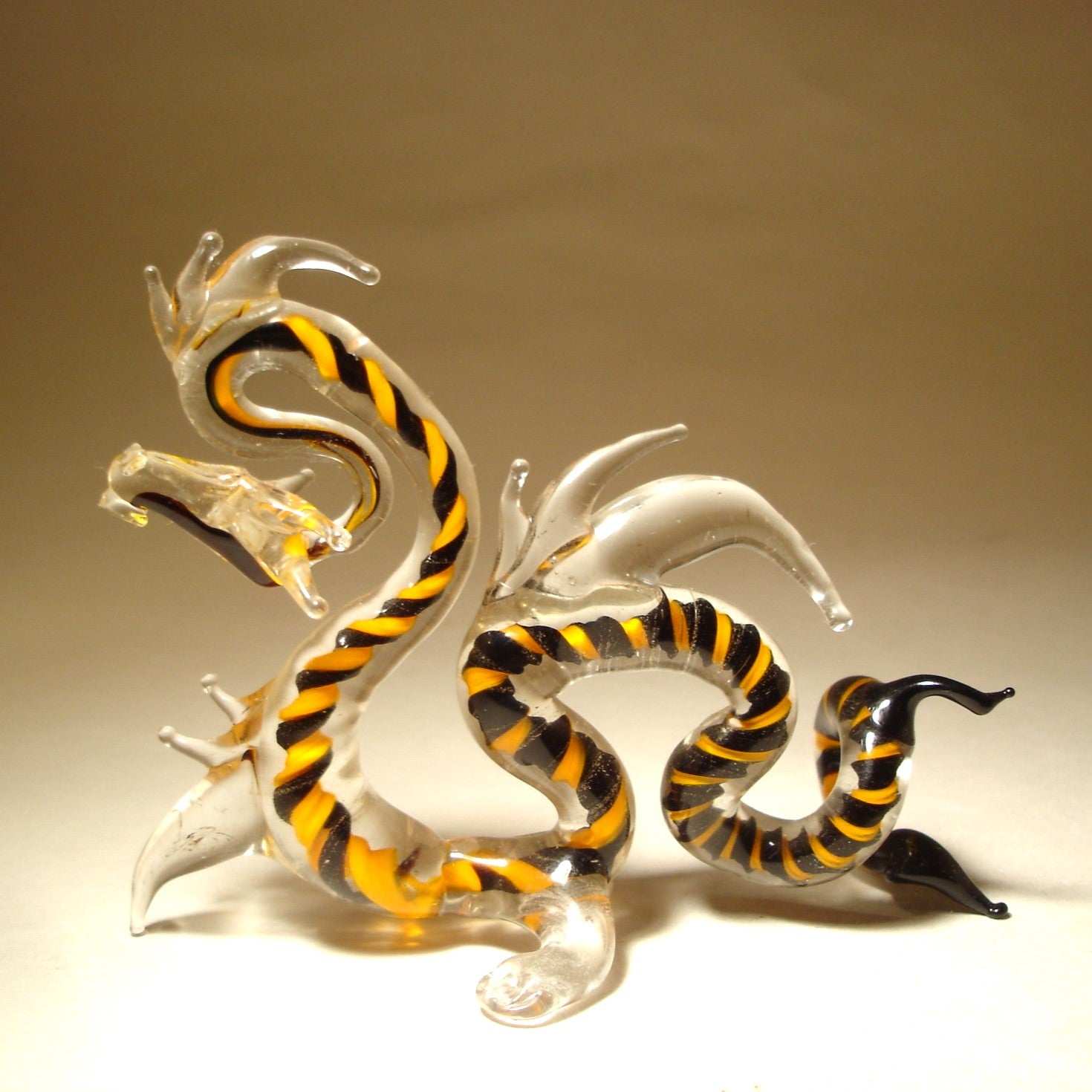 A close-up of the glass Chinese dragon figurine, focusing on the fine details of its face, flowing mane and curled tail.