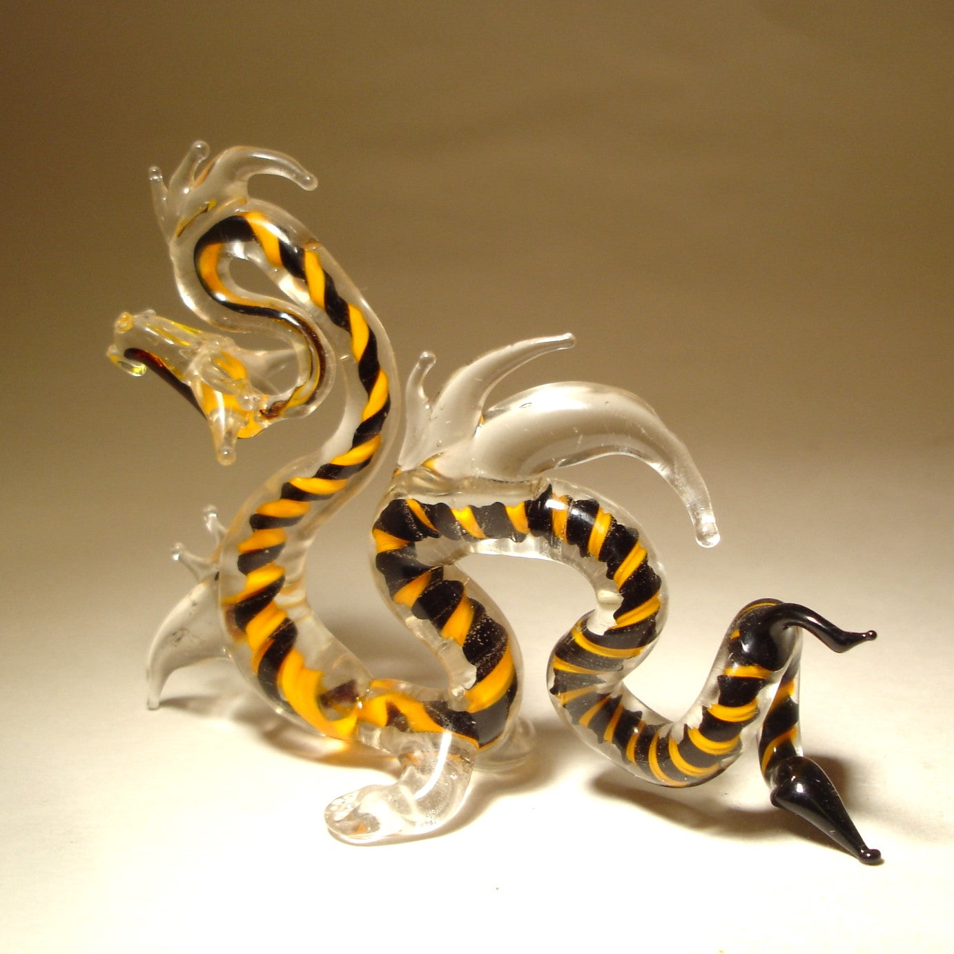 A glass Chinese dragon figurine with intricate detailing, featuring the dragon in a coiled stance with its mouth open, symbolizing power.