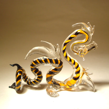 A side profile of the glass Chinese dragon figurine, showcasing the long, serpentine body with black and orange stripes.