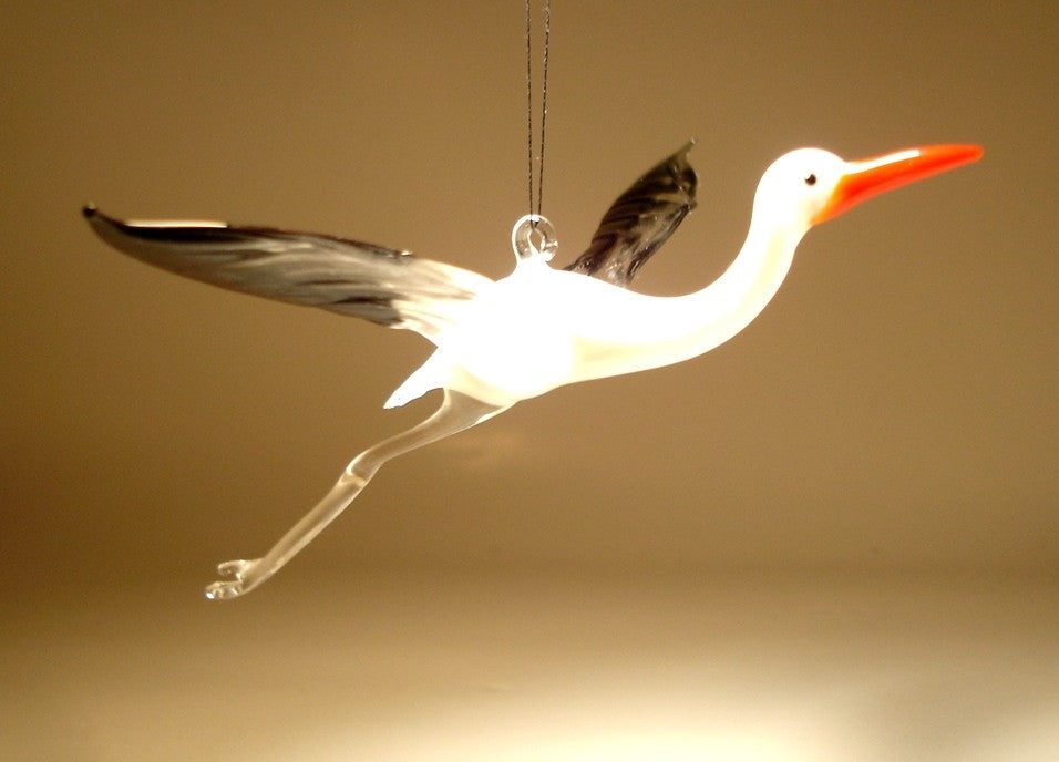 A side view of a glass stork egret ornament figurine, highlighting the elegant curve of its neck and outstretched wings in black and clear.