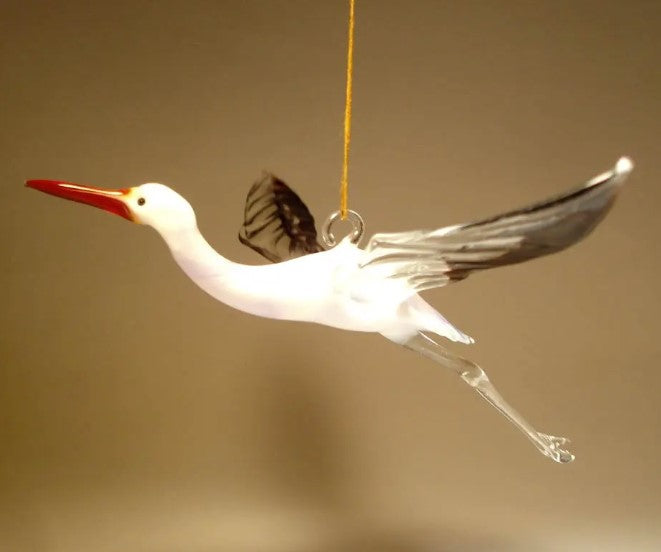 A front view of a white glass stork egret ornament figurine, showcasing its slender neck, long legs, and red pointed beak.