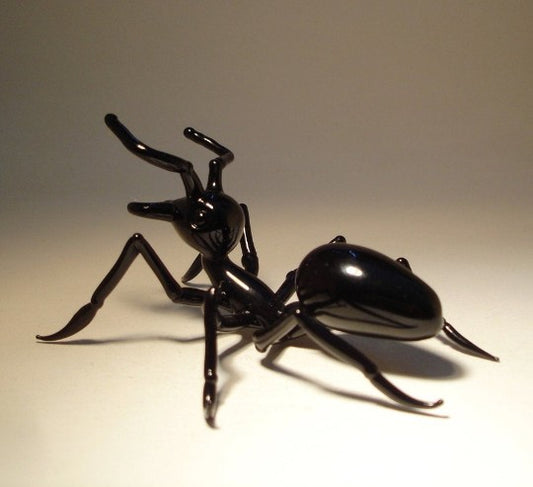 Side view of a glass ant figurine, highlighting the intricate design of its legs and antennae.