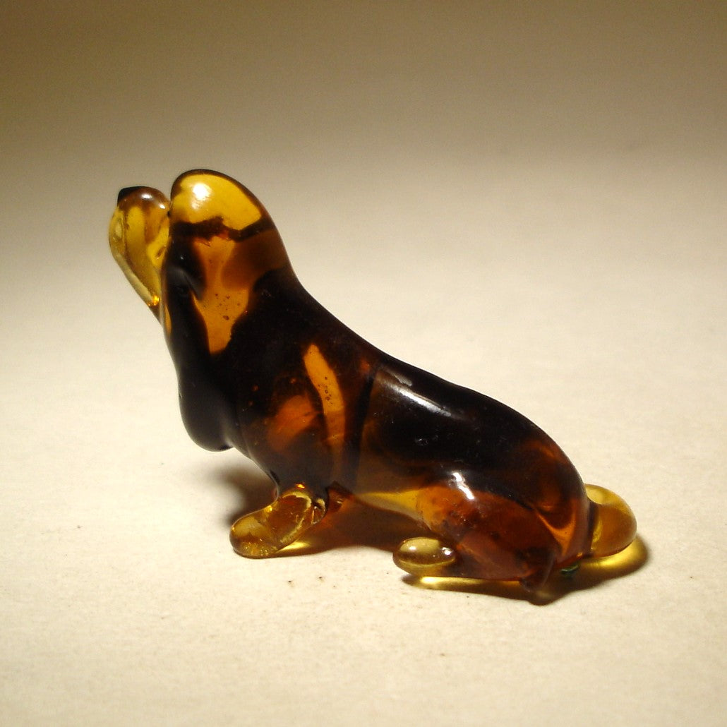 Side view of the glass Basset Hound figurine's face, capturing the long ears and gentle demeanor that defines this beloved breed