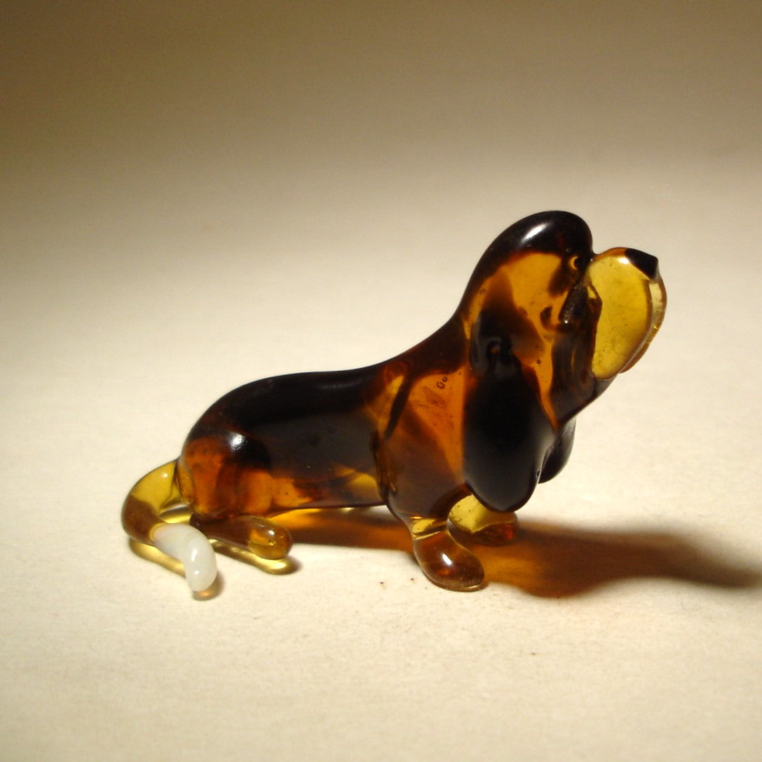 Handcrafted glass Basset Hound figurine sitting, showcasing its distinctive long ears and droopy expression.