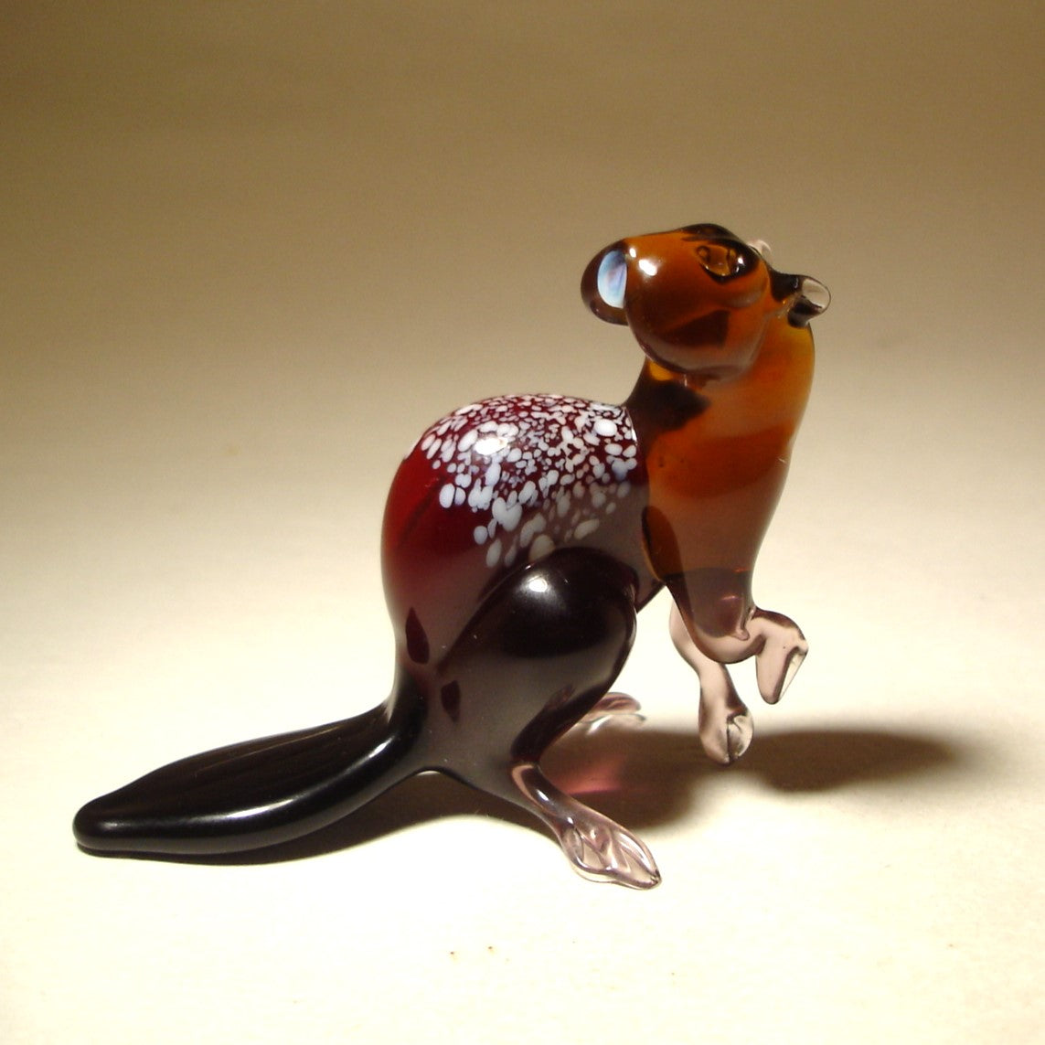 Side view of a glass beaver figurine, highlighting its pose with its head turned back.