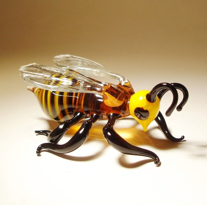 Close-up view of the glass bee figurine, focusing on the detailed craftsmanship of its antennae, wings, and yellow head.