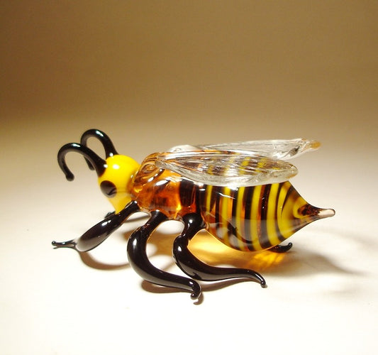 Side view of a glass bee figurine, highlighting the intricate wing design and black and yellow striped body.