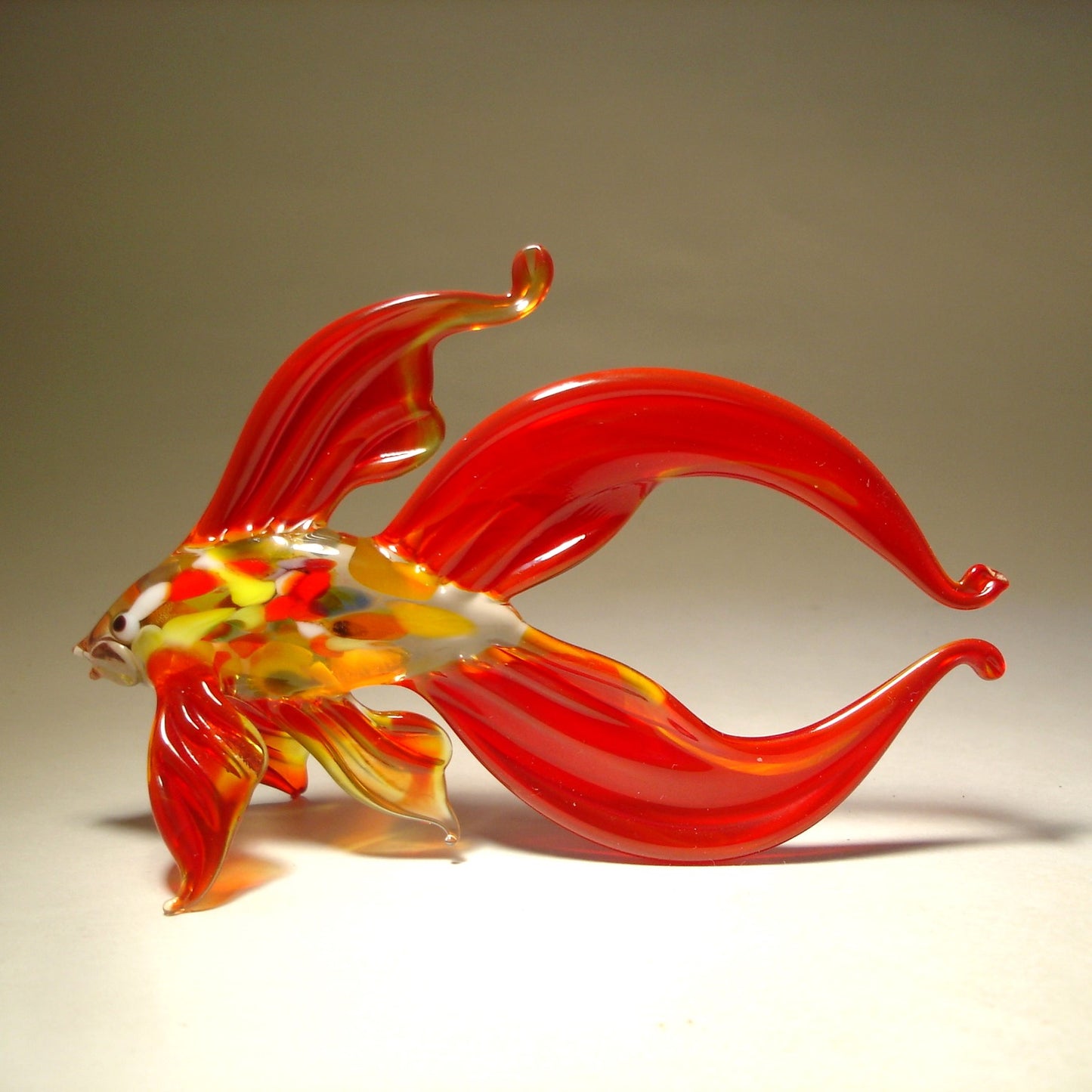 A close-up view of a red glass betta fish figurine, capturing the intricate details of its scales and the delicate edges of its fins.