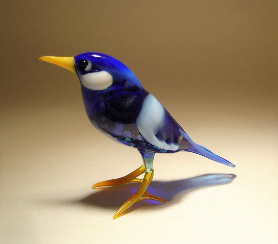 Front view of the glass bluebird figurine, focusing on its intricate beak, feathers, and glossy blue color.