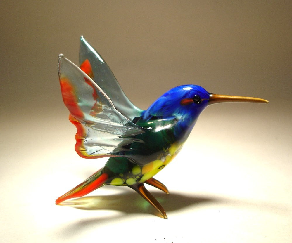 A glass hummingbird with a striking blue head, showing the figurine's elegant shape and vibrant colors.