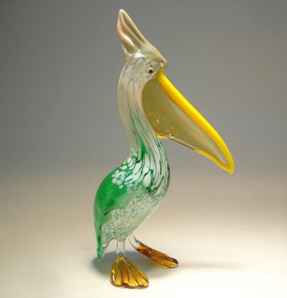 Side view of the glass pelican, illustrating its graceful posture and the captivating contrast between the green and white body and the translucent yellow pouch. 