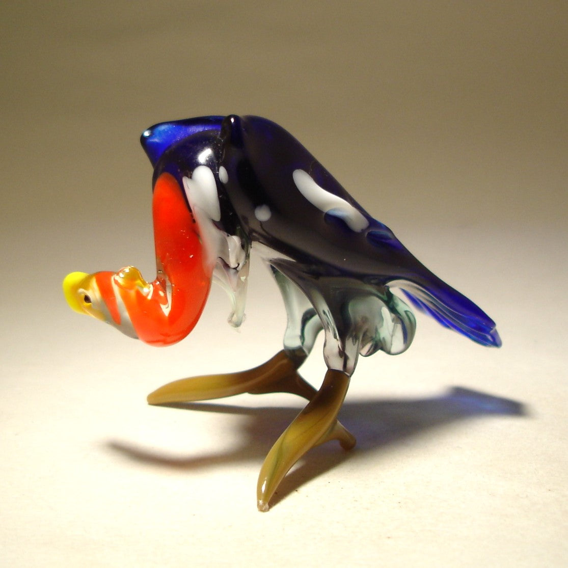 Side view of the blue glass buzzard vulture figurine, focusing on the fine craftsmanship of its head and orange neck.