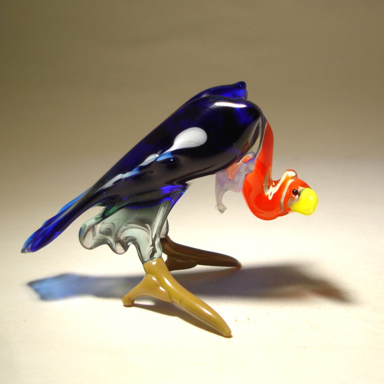 Side view of a glass vulture figurine, highlighting its hunched posture and intricate wing design.