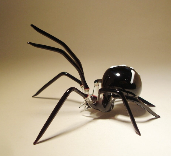 Side view of the black glass spider figurine, highlighting the intricate shape of the spider's legs