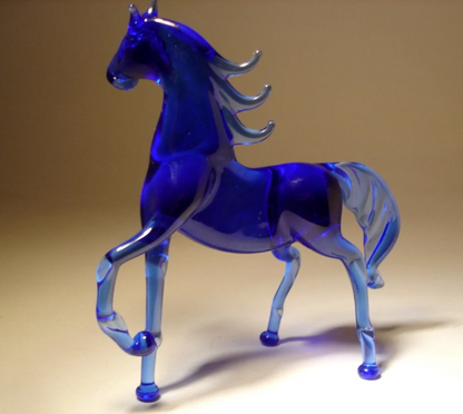 opposite side view of the blue glass horse figurine, highlighting its graceful curves and flowing mane and tail