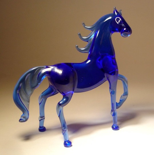 side view of a blue glass horse figurine, showcasing its elegant stance with a raised front leg