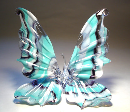 A front view of a white, blue and black striped glass butterfly figurine with intricately designed wings.