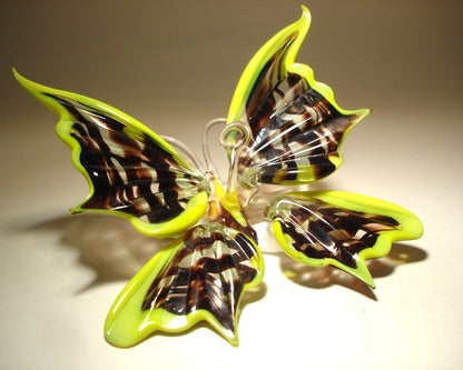 Another side view of the handmade glass butterfly, with open wings trimmed in yellow and black and clear stripes in the middle.