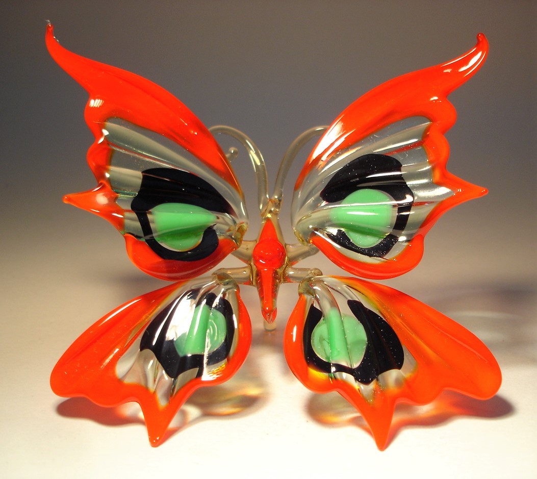 Handcrafted glass butterfly figurine with red, green, and black wings, featuring intricate patterns.