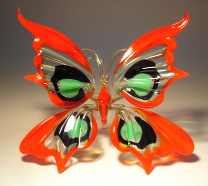 Handcrafted glass butterfly figurine with red, green, and black wings, featuring intricate patterns.