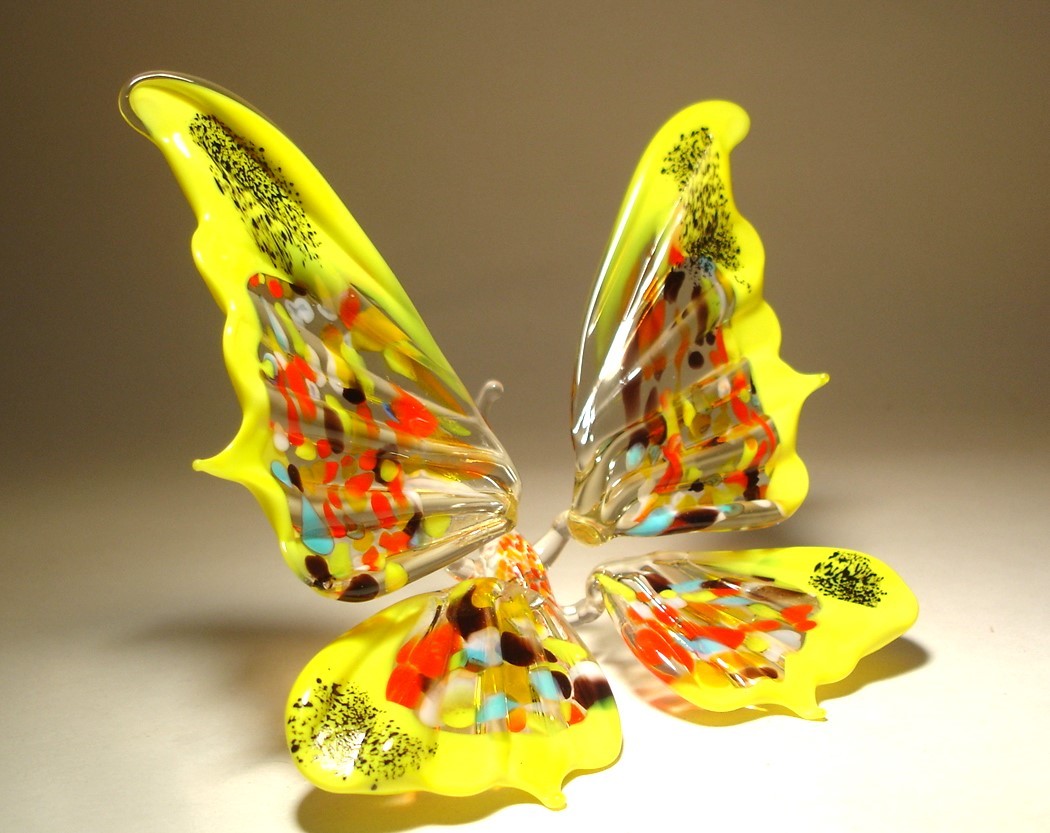 Side view of the yellow and red glass butterfly figurine sitting with its wings fully extended. 