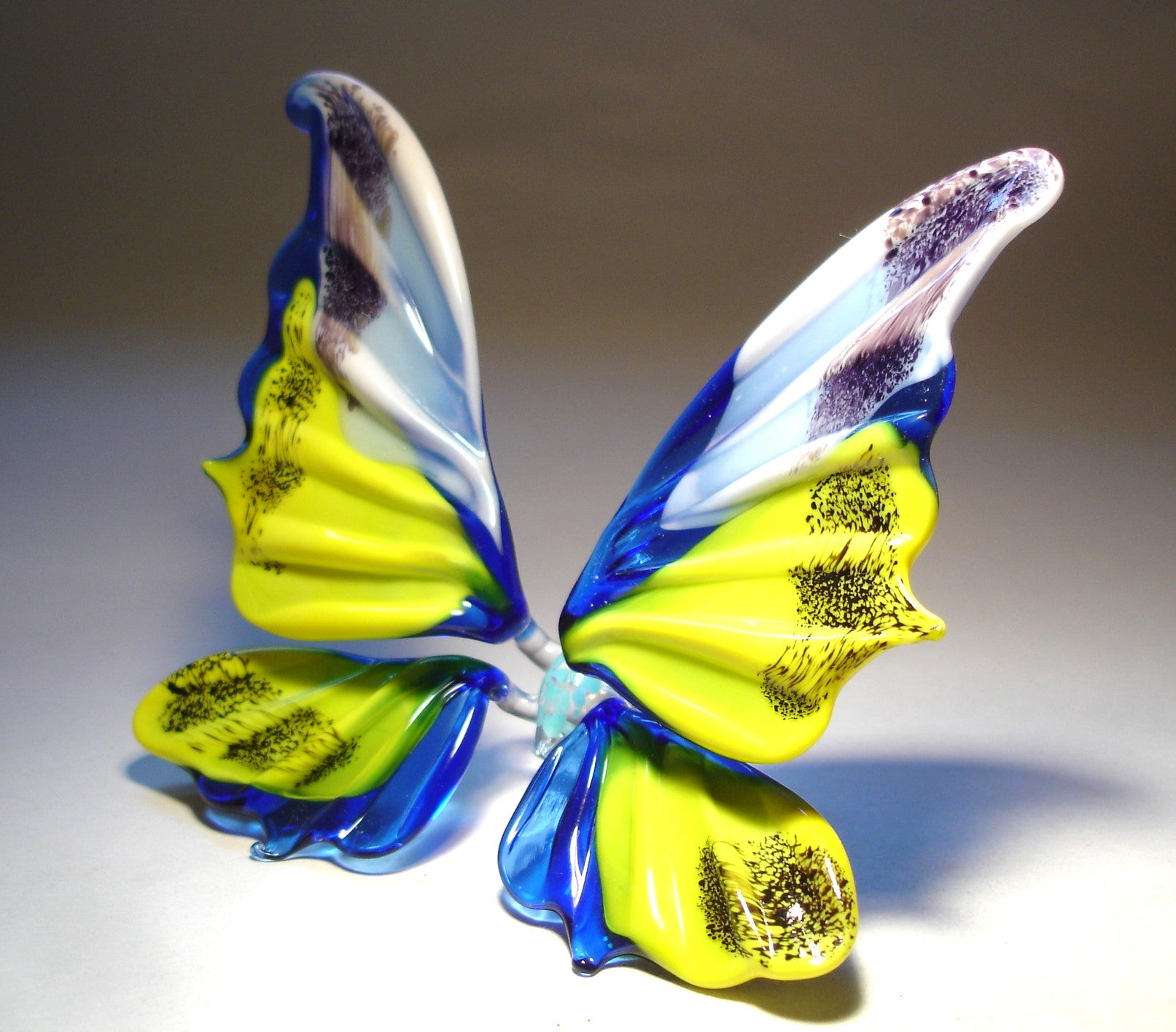 The blue, yellow and white glass butterfly turned to the left